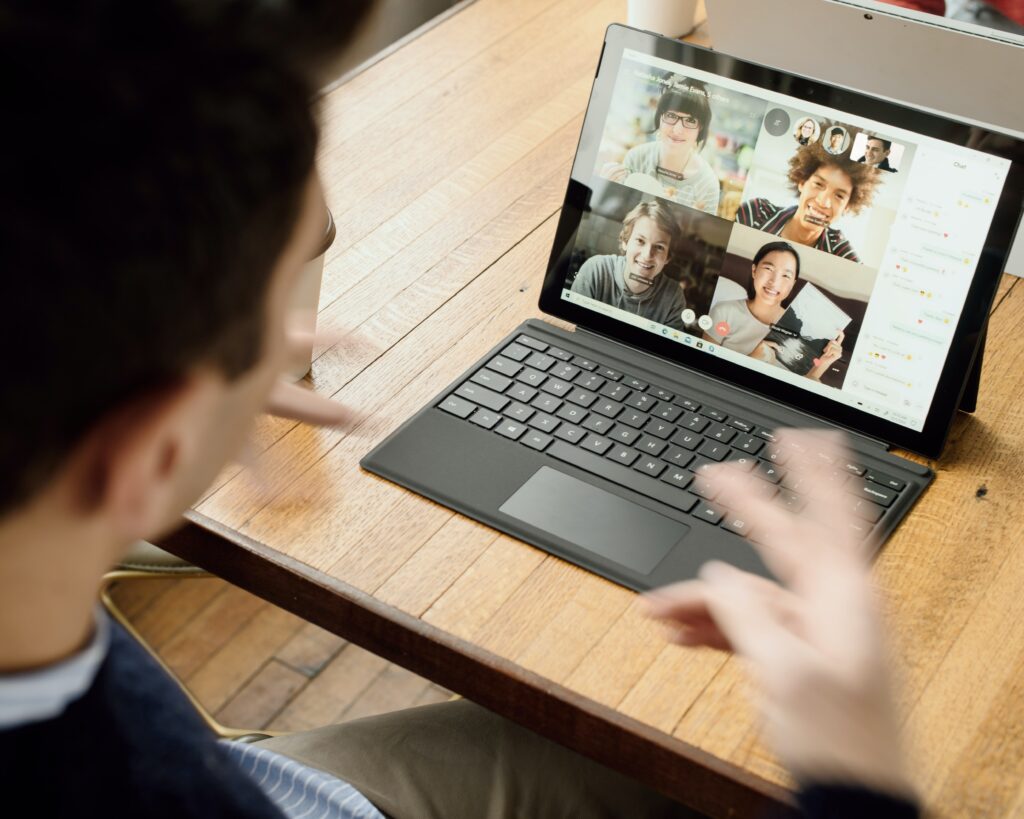 Photo of a person using a laptop to participate in a group conversation via videoconferencing
