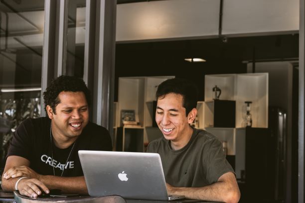 Photo of two young men looking together at a laptop